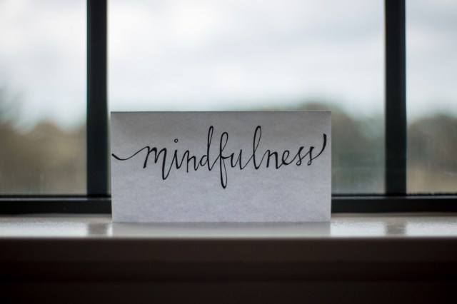 A handwritten note reading "mindfulness" sits on a ledge in front of a misty window.