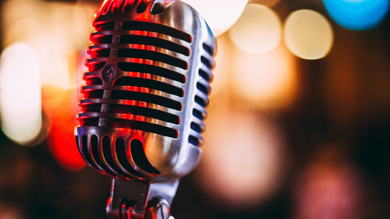 Silver old style microphone with blurred out lights in the background.