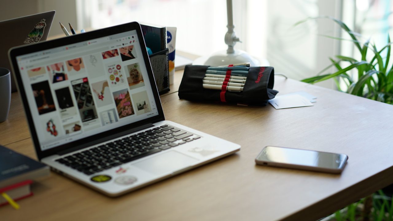 A desk top with a laptop computer and smartphone laying out on it