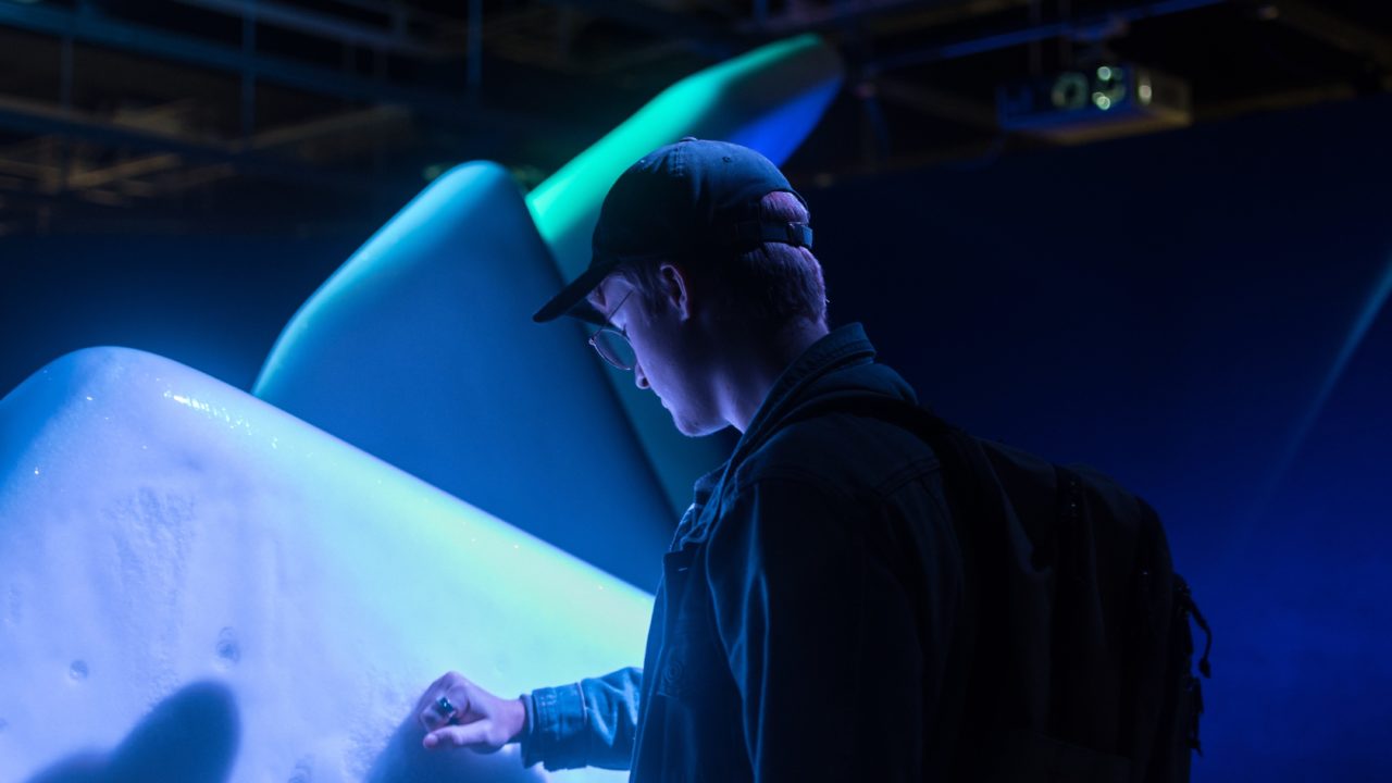 A museum visitor touching a display of an ice cap