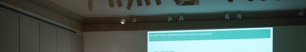 Speakers at a podium addressing an audience, in front of a presentation slide that says "size of collection" with a chart