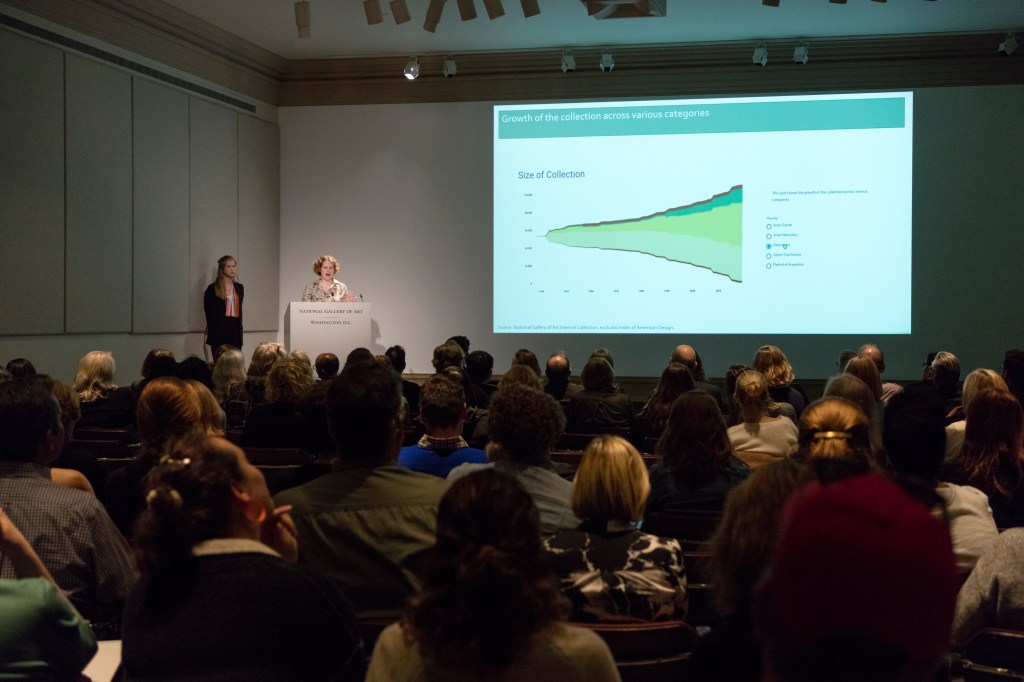 Speakers at a podium addressing an audience, in front of a presentation slide that says "size of collection" with a chart