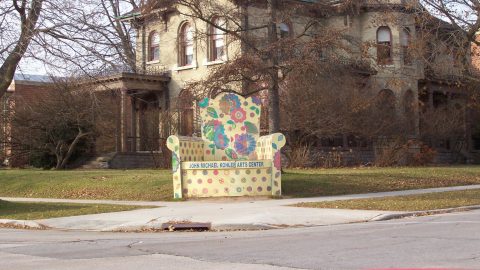 Exterior of a building with a large chair-shaped sculpture outside.