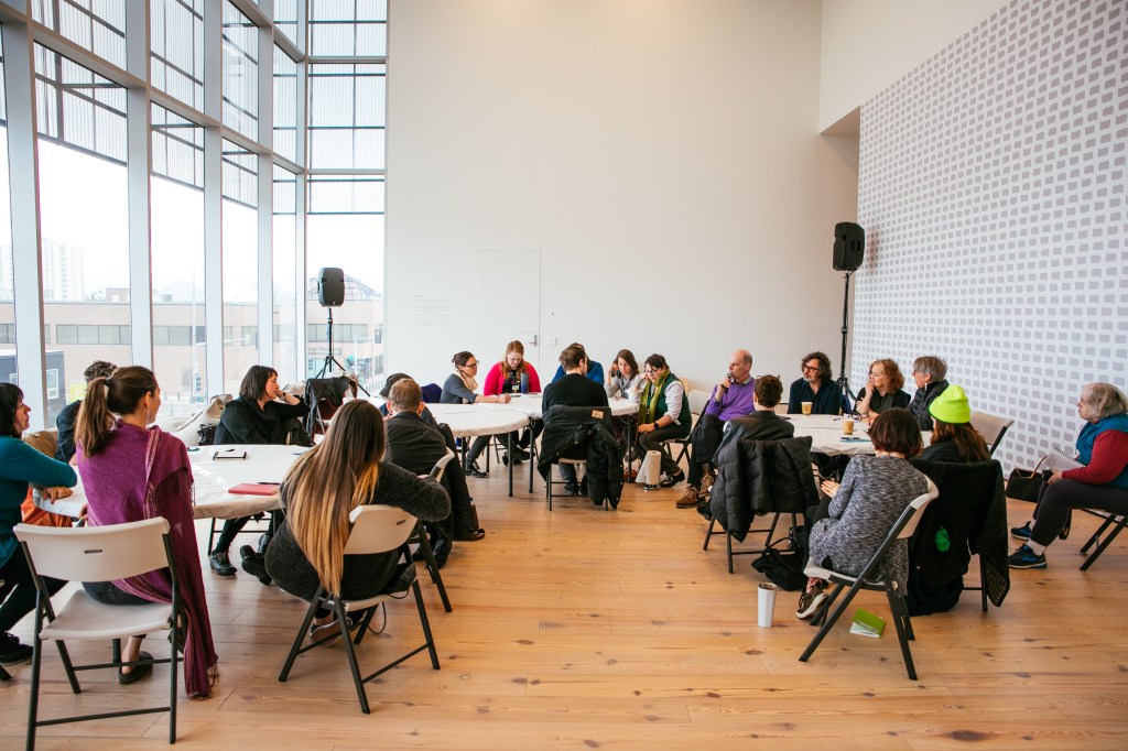 A workshop with people sitting at tables in a conference room