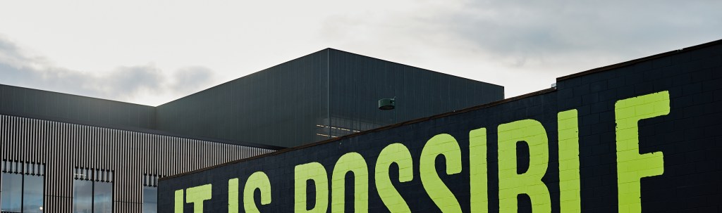 A black-painted building with bright green lettering reading "It is Possible"