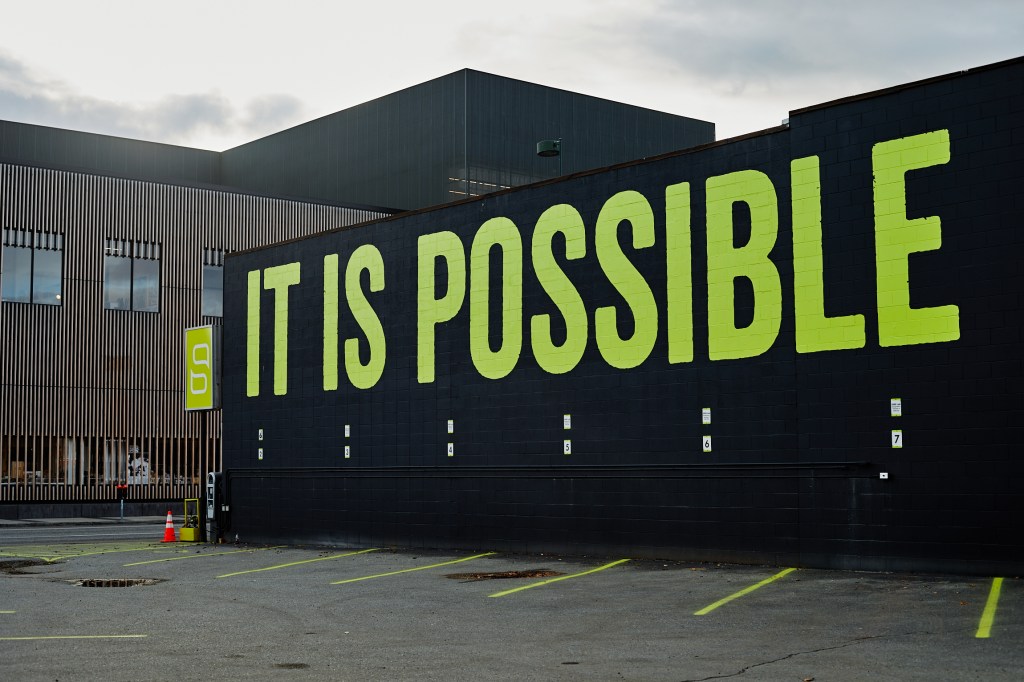 A black-painted building with bright green lettering reading "It is Possible"