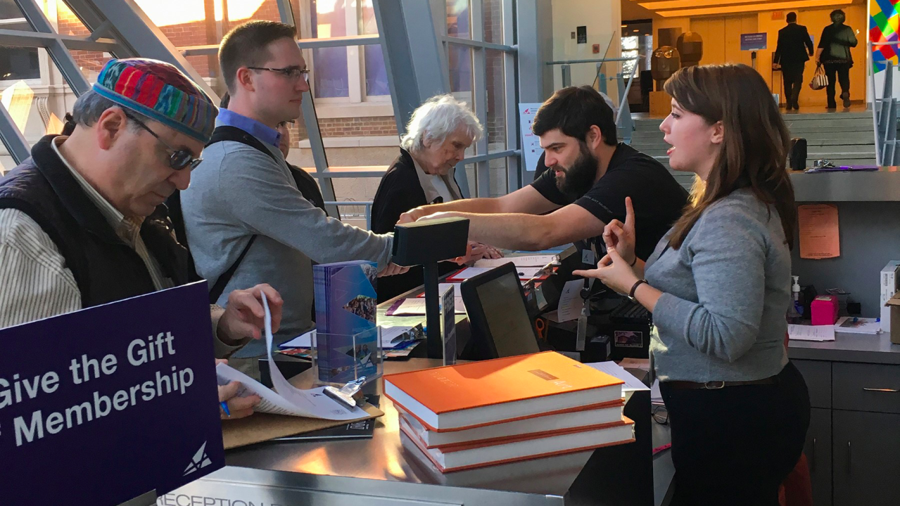 Staff receiving guests behind an admissions desk