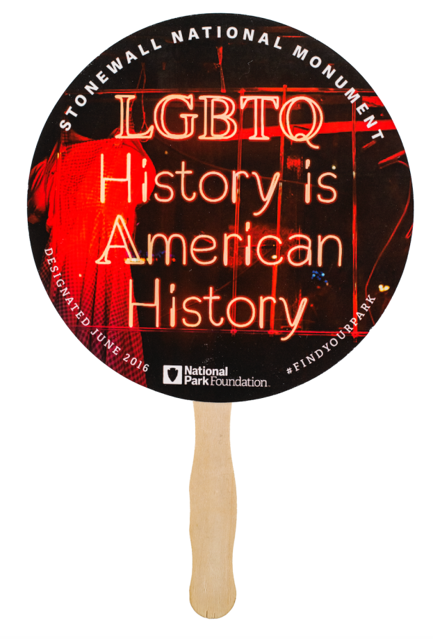 A paper fan reading "Stonewall National Moneument: LGBTQ History is American History. Designated June 2016. National Park Foundation. #FindYourPark."