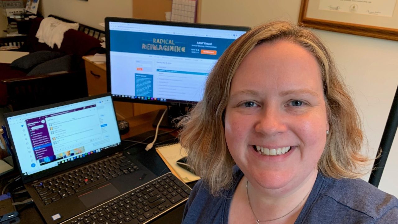 Laura Lott smiling in front of computers open the virtual conference program