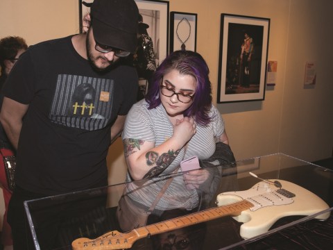 A man and a woman examine a white guitar in a case.