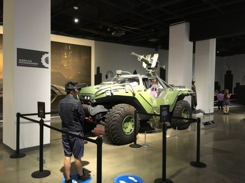 A visitor inside a museum wearing a virtual reality headset in front of a vehicle