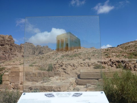 A landscape viewed through a sheet of glass, which makes it appear that a building is standing atop a hill.