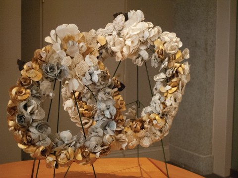 Two white, silver, and gold wreath's sit in a corner. 