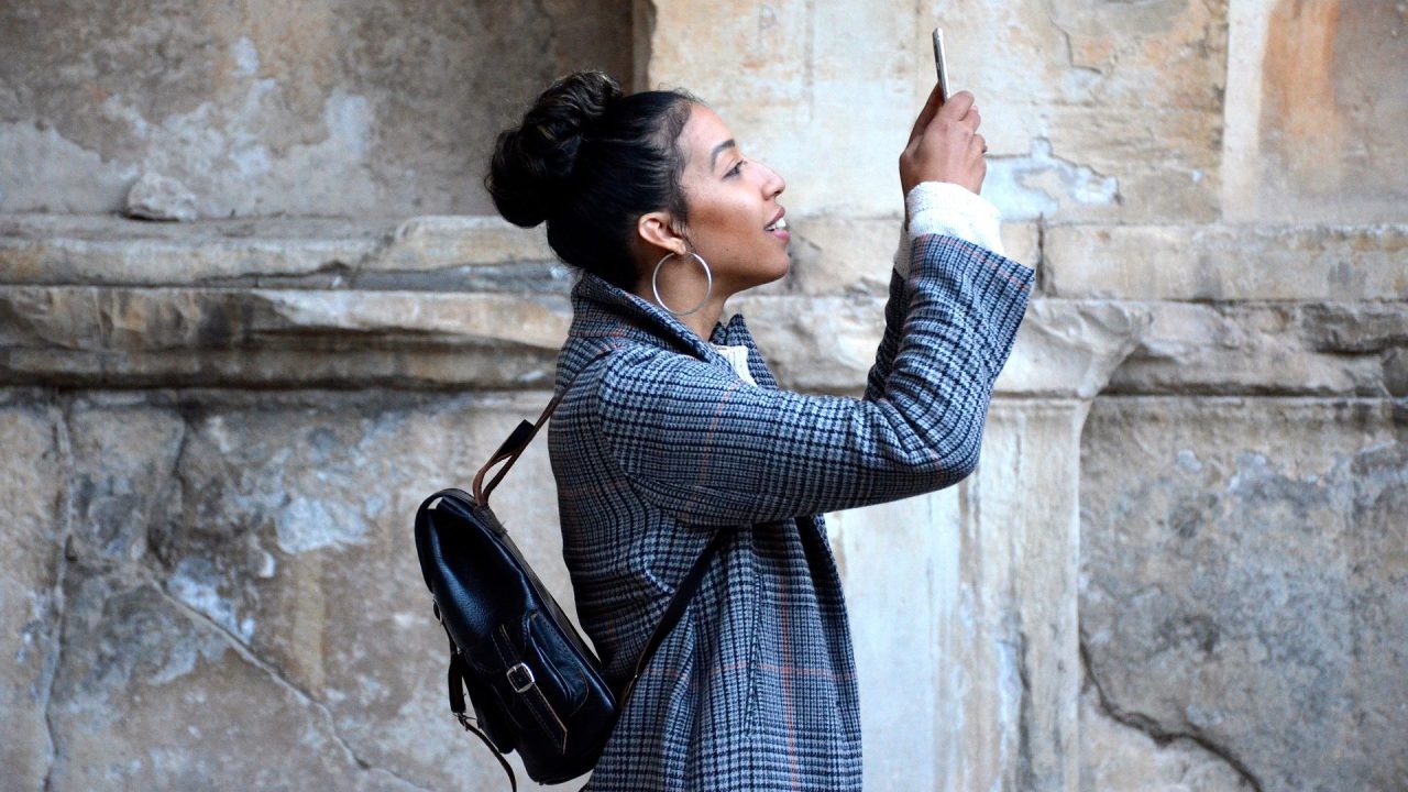 A person holding up a phone to take a picture and smiling