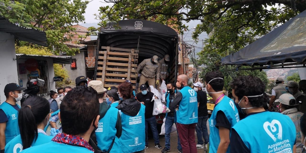 Masked volunteers standing in front of an open truck distributing supplies