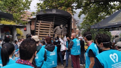 Masked volunteers standing in front of an open truck distributing supplies