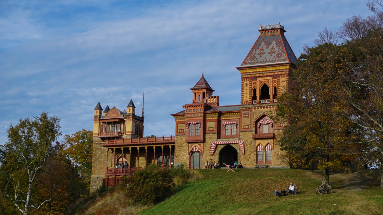An exterior of a large historic house perched on a hill