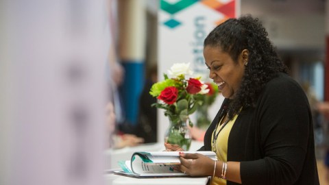 An attendee at the AAM Annual Meeting & MuseumExpo looking at a magazine and smiling