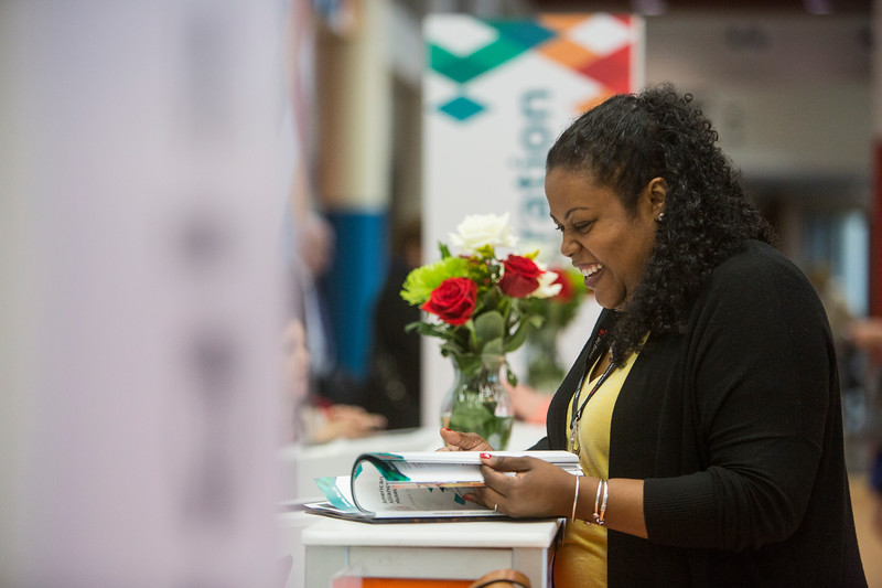 An attendee at the AAM Annual Meeting & MuseumExpo looking at a magazine and smiling