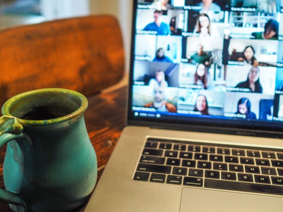 A laptop open to a Zoom conversation with a mug in the foreground