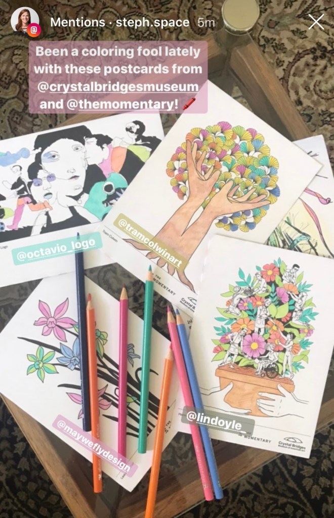 Screenshot of an Instagram post with the caption "Been a coloring fool lately with these postcards from @crystalbridgesmuseum and @themomentary!" and a photo of half-colored postcards and coloring pencils.