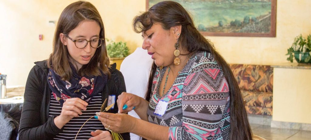 A Native community member standing next to a student pointing at an object for inspection