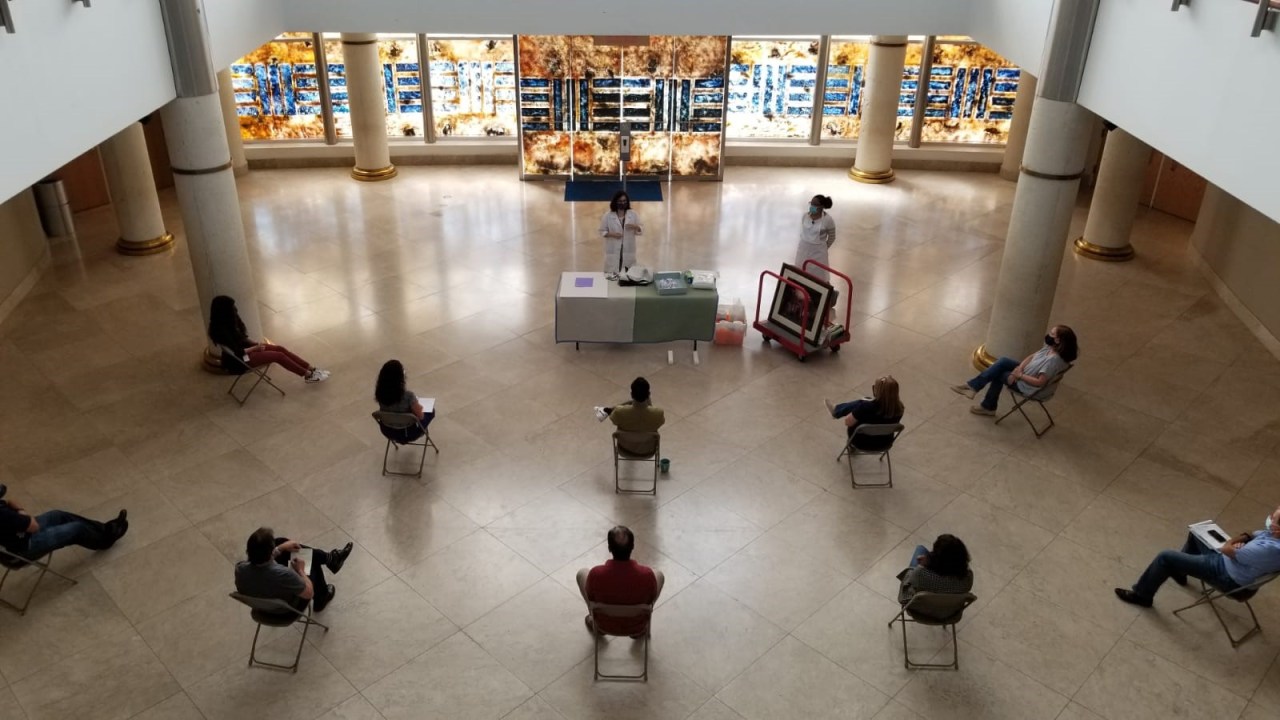 Aerial view of people sitting spaced out and wearing masks in a museum setting