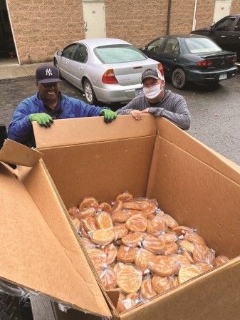 Two men, one wearing a mask, load 250 loaves of donated fresh-baked bread onto the truck.
