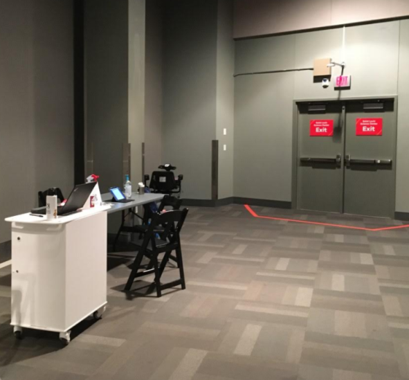 A small folding table in an empty area of a museum, with laptops open on the table.