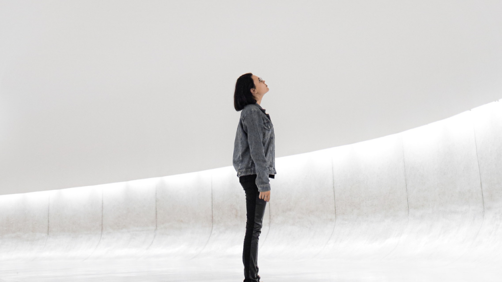A person standing in a museum gallery looking up toward the ceiling