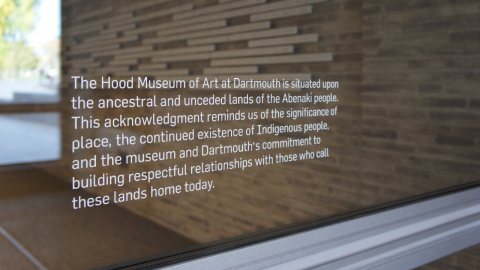 A decal on a window reading "The Hood Museum of Art at Dartmouth is situated upon the ancestral and unceded lands of the Abenaki people. This acknowledgment reminds us of the significance of place, the continued existence of Indigenous people, and the museum and Dartmouth's commitment to building respectful relationships with those who call these lands home today."