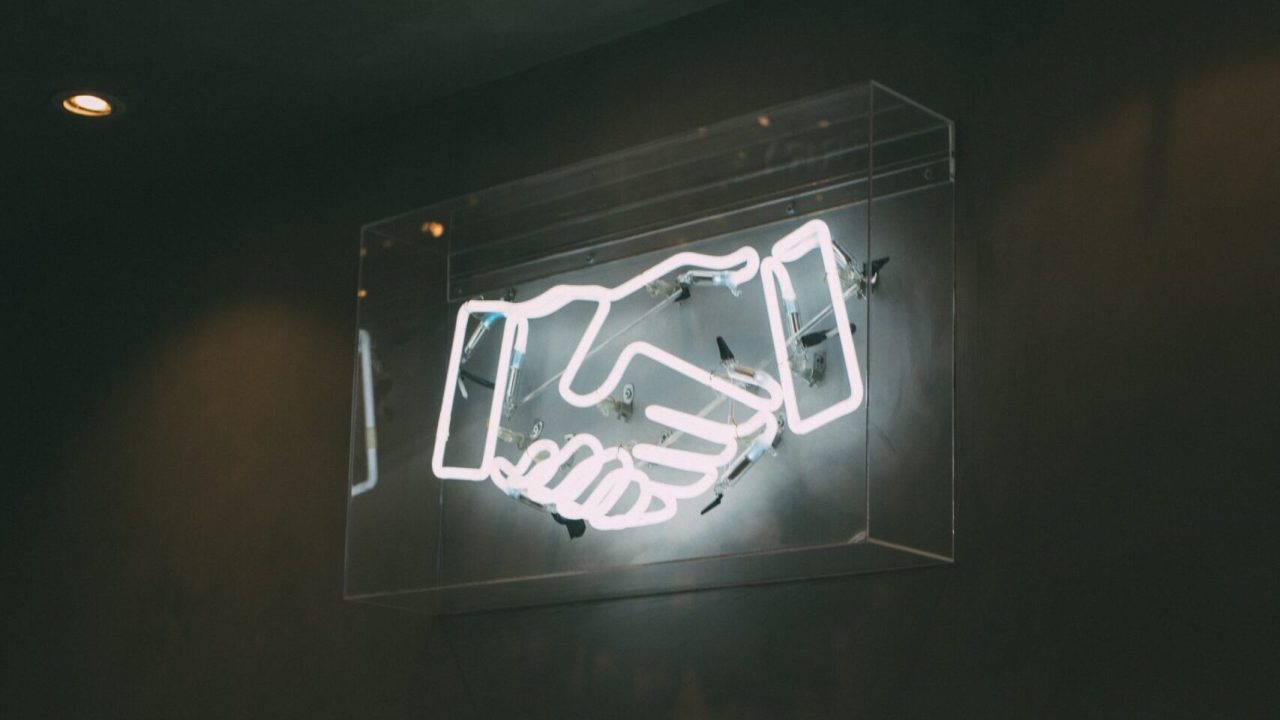 A neon sign depicting a handshake