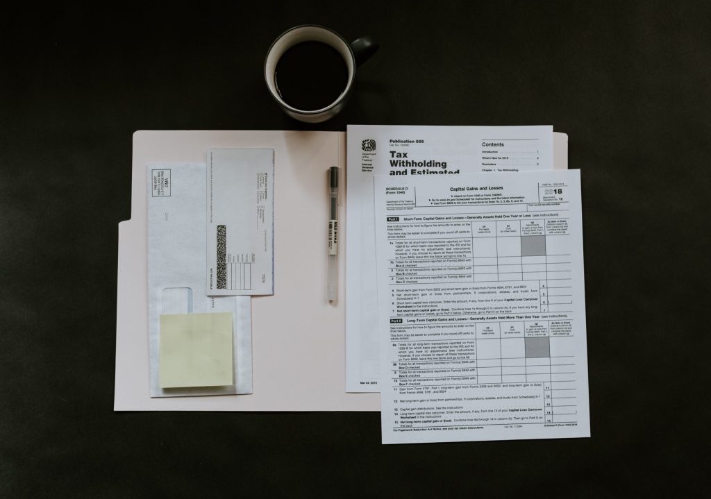 A file folder of forms laid out with a Muji pen and a mug of black coffee