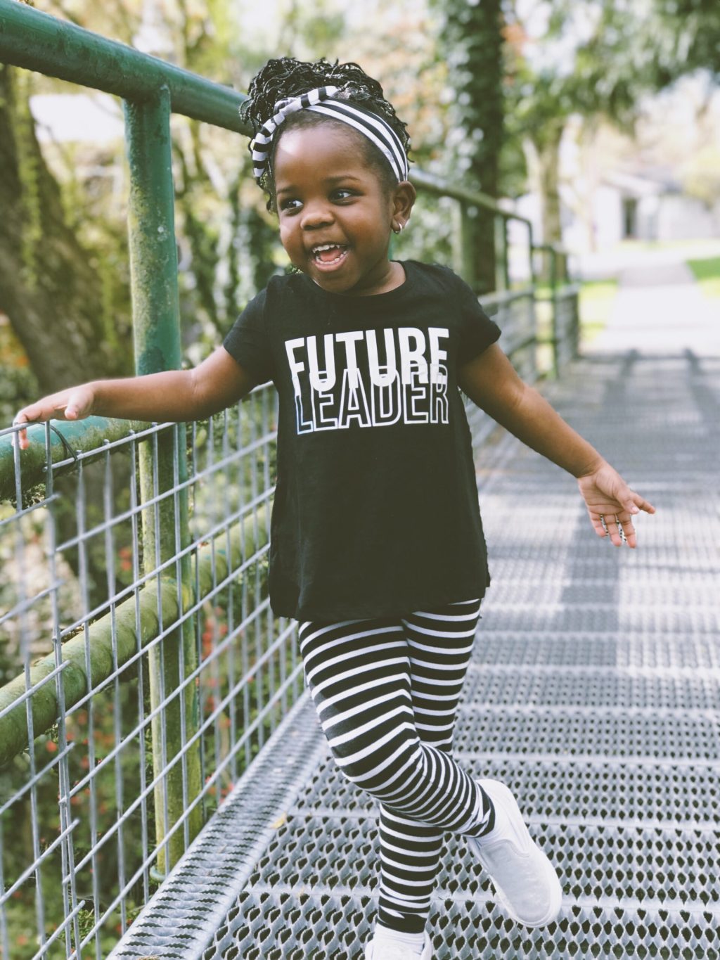 A young child standing on a bridge wearing a t-shirt reading "Future Leader"