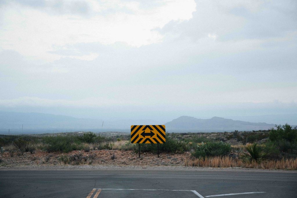 A two-way arrow road sign at a forked road in the desert