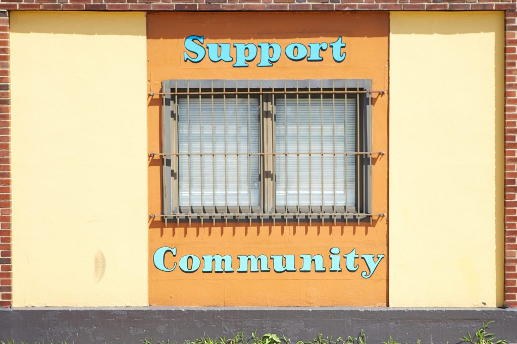 A colorful wall and window with the message "Support Community" painted on it