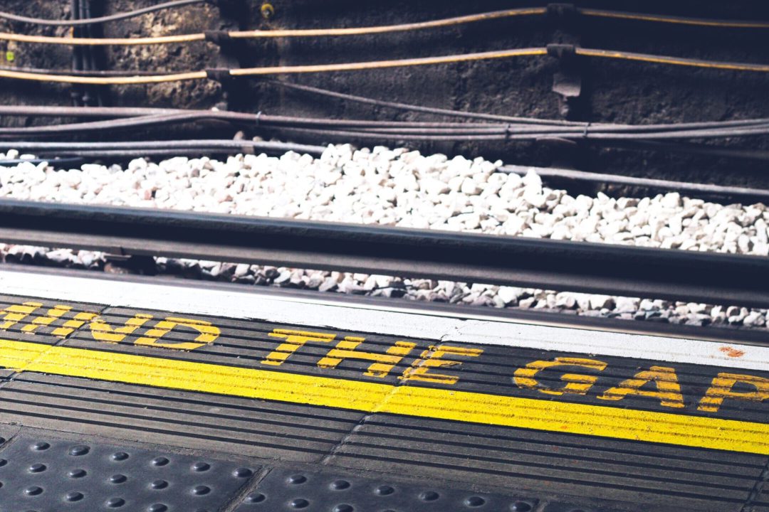 The edge of a train platform with the slogan "mind the gap" written near the edge