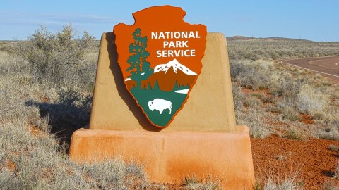 A sign with the National Park Service logo on it, in from of a desert landscape