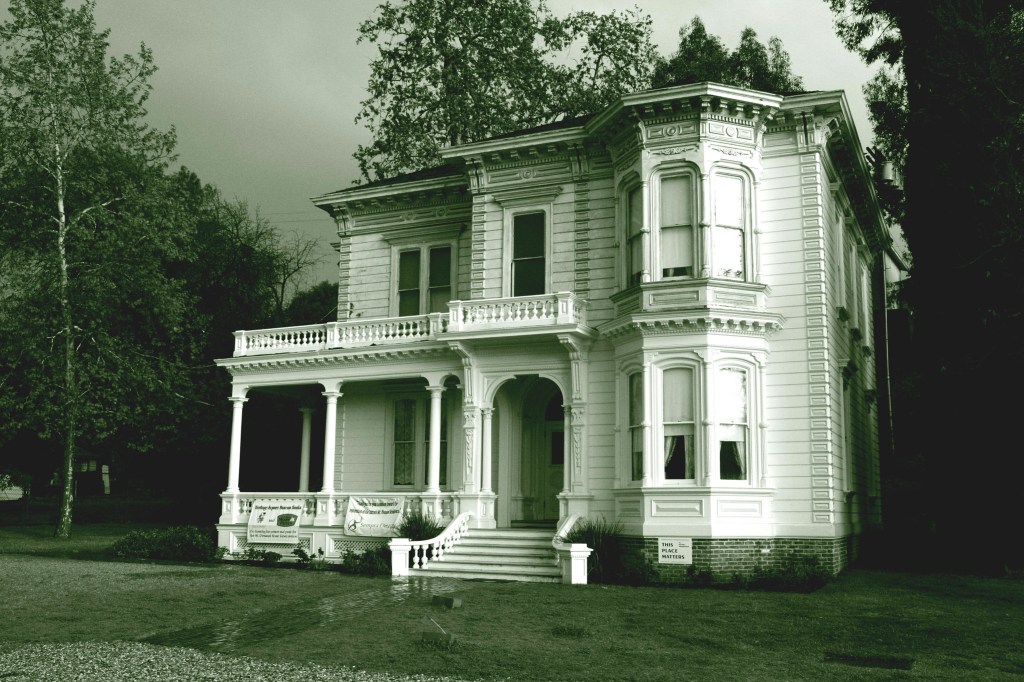 A sepia-colored photograph of a Victorian mansion