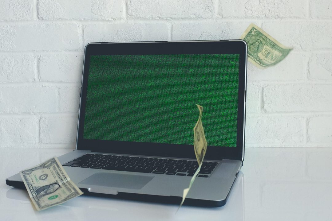 A laptop with dollar bills raining down on it