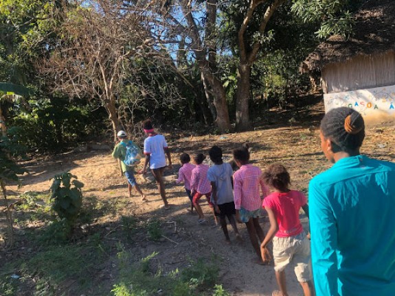 A line of students followed by a teacher entering the woods