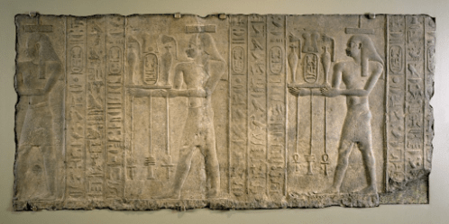 A carved relief showing human figures next to hieroglyphic symbols