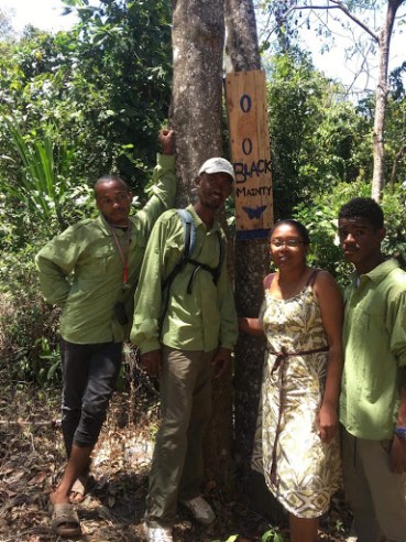 Staff posing in front of a wooden box in the forest