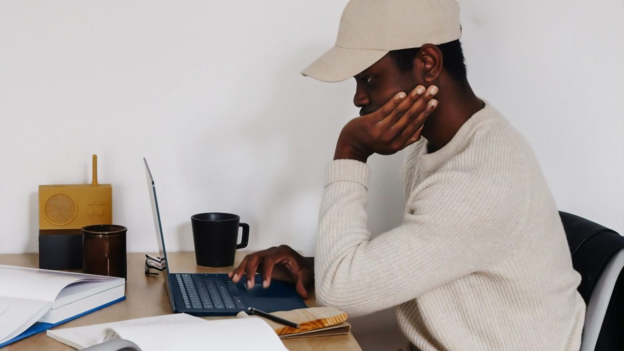 A young person sitting at a table in a home working on a laptop