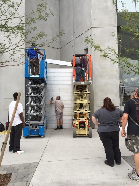 A team of workers stacking metal rods as a barrier in front of a building