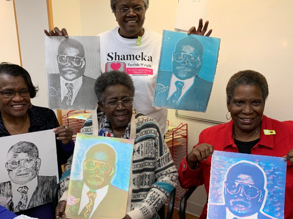 A group of people holding up pop art portraits of a Black man