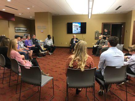 A group of students sitting in a circle listening to the ambassador speak