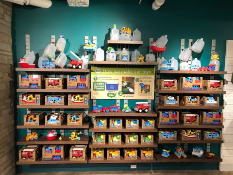 A wall of toys displayed with a sign reading "How we make our toys" explaining they are made of 100 percent plastic. 