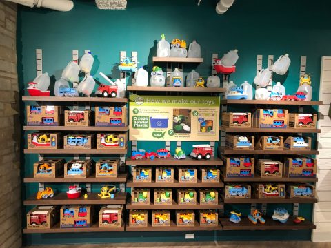 A wall of toys displayed with a sign reading "How we make our toys" explaining they are made of 100 percent plastic.