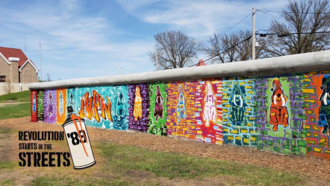 A wall painted with graffiti-style art of elephants and lettering with the title "Revolution Starts in the Street" overlaid on the image